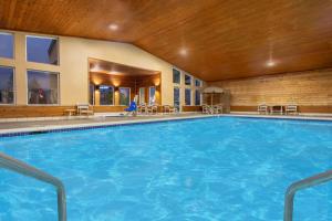 Una gran piscina en un hotel con sillas y mesas. en AmericInn by Wyndham Boscobel, en Boscobel