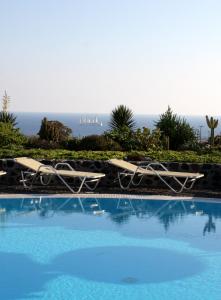 a swimming pool with chairs and the ocean in the background at Kalimera Hotel in Akrotiri