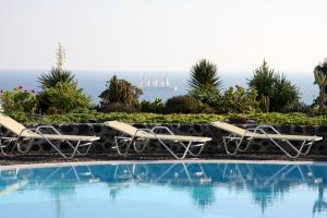 a pool with chairs and a view of the ocean at Kalimera Hotel in Akrotiri