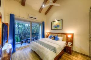 um quarto com uma cama e uma varanda em Joystreet - Beachy Blossom em Siolim