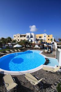 a large blue swimming pool with chairs and buildings at Kalimera Hotel in Akrotiri