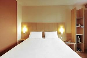 a large white bed in a room with two lamps at ibis Besançon Marchaux in Marchaux