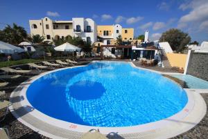 a large swimming pool with chairs and buildings in the background at Kalimera Hotel in Akrotiri
