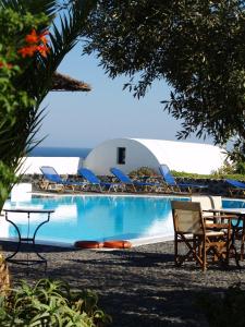 a pool with chairs and a table and a building at Kalimera Hotel in Akrotiri