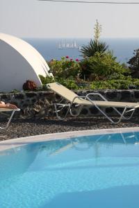 a chair and an umbrella next to a swimming pool at Kalimera Hotel in Akrotiri