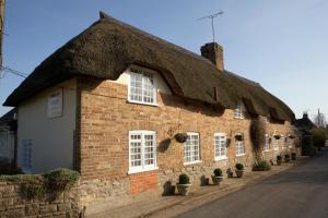 an old brick building with a thatched roof at Yalbury Cottage in Dorchester +9 photos