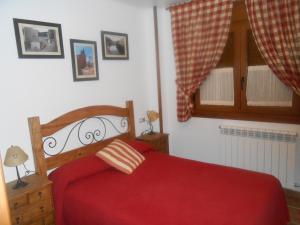 a bedroom with a red bed and a window at Villa Maria in La Virgen de la Vega