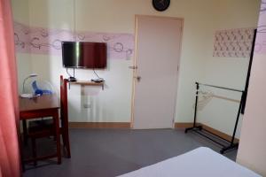 Zimmer mit einem Bett und einem TV an der Wand in der Unterkunft Nellie's Place in Puerto Princesa