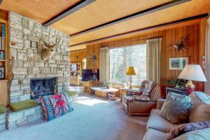 sala de estar con chimenea de piedra y muebles de cuero en Mountain and River View Cliff House, en Graeagle