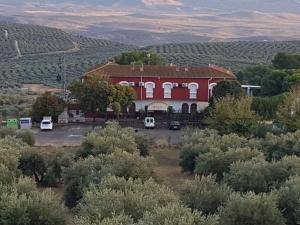 un gran edificio rojo con un aparcamiento enfrente en Hotel-Restaurante la Loma, en Baeza