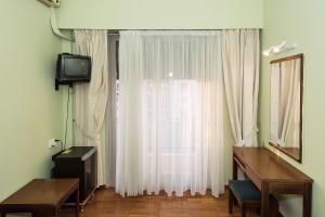 a room with a window with a television and a desk at Hotel Alexandros in Volos