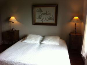 um quarto com uma cama branca com 2 candeeiros e uma fotografia em La maison aux prés em Durbuy