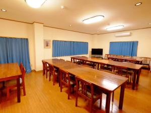 a classroom with wooden tables and chairs and blue curtains at Kokumin Shukusha Sun Marina in Kaminato