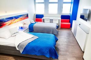 two beds in a room with two red chairs at Hostel Umed in Łódź