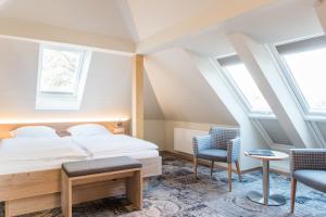 a bedroom with a bed and two chairs at Hotel Bellevue in Lauenburg