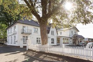 a white house with a white fence and a tree at Hotel Bellevue in Lauenburg