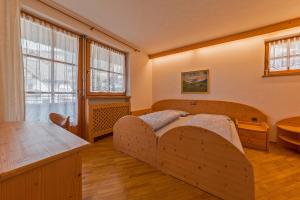 una camera con letto in legno e ampia finestra di LERCHER Anna Villa Lercher a San Candido