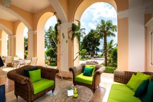 a porch with wicker chairs and green cushions at Hotel Kvarner Palace in Crikvenica
