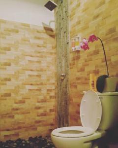 a bathroom with a toilet and a lamp on the wall at Valomia Beachfront in Amed