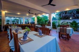 a dining room with white tables and chairs and windows at P5 Angkor Residence in Siem Reap