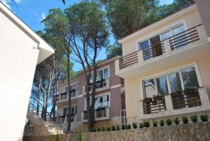 an apartment building with balconies and trees in the background at Hotel Art Media in Herceg-Novi