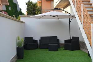 a patio with an umbrella and chairs and grass at B&B Le Mansarde in Pescara
