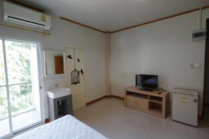 a room with a bed and a television and a sink at Baan Malee in Phuket Town
