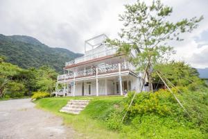 una gran casa blanca en una colina con un camino de tierra en Songhe ShanShuei B&B en Heping