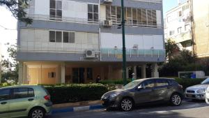 grupa samochodów zaparkowanych przed budynkiem w obiekcie Blau Guesthouse w mieście Netanja