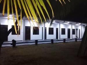 Quench Inn في أمبارا: مبنى أبيض بنوافذ سوداء و نخلة