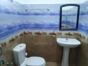 a bathroom with a toilet and a sink and a mirror at Quench Inn in Ampara