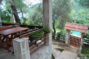 a patio with a wooden table and a fence and trees at Hotel Art Media in Herceg-Novi