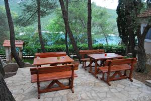 three picnic tables and benches sitting on a stone patio at Hotel Art Media in Herceg-Novi
