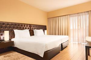 a bedroom with a large bed and a large window at Hotel dos Zimbros in Sesimbra