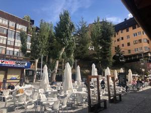 grupa stołów i krzeseł z białymi parasolami w obiekcie Apartamento Plaza Pradollano 2 w mieście Sierra Nevada