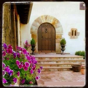 an entrance to a building with a wooden door and purple flowers at Posada Rural Lindos Sueños in La Lomba