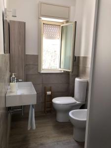 a bathroom with a toilet and a sink and a window at La casa dei sassi holiday house in Giardini Naxos