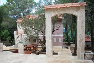 a stone archway with a picnic table in front of a house at Hotel Art Media in Herceg-Novi