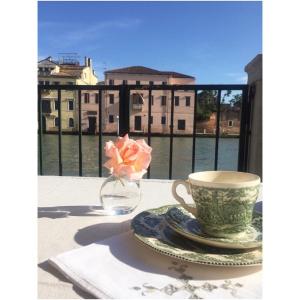 una mesa con una taza y un jarrón con una flor en Terrazza Momon, en Venecia