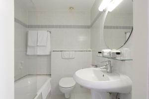 a bathroom with a sink and a toilet and a mirror at Theater Hotel Leuven Centrum in Leuven