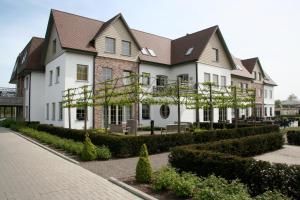 a large white house with trees in front of it at Biznis Hotel in Lokeren