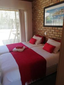 a bedroom with two beds with red and white sheets at Windmill Guest House Bloemfontein in Bloemfontein