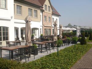a patio with tables and chairs with umbrellas at Biznis Hotel in Lokeren