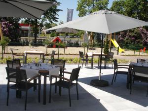 a group of tables and chairs with white umbrellas at Biznis Hotel in Lokeren