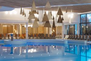 uma piscina com cadeiras e mesas num edifício em Hotel Ajda - Terme 3000 - Sava Hotels & Resorts em Moravske-Toplice
