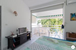 a bedroom with a bed and a tv and a balcony at Agréable cocon à la Marina de la pointe du bout in Les Trois-Îlets