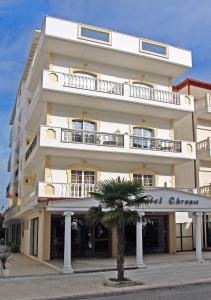 a tall white building with a palm tree in front of it at Hotel Chronis in Paralia Katerinis