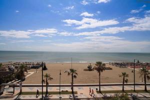 a view of a beach with palm trees and the ocean at Hotel Tarik in Torremolinos