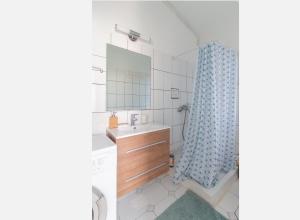 a bathroom with a sink and a shower curtain at Agréable cocon à la Marina de la pointe du bout in Les Trois-Îlets