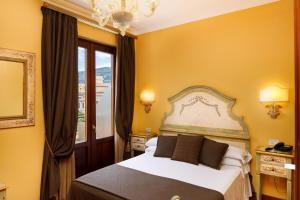 een slaapkamer met een bed met gele muren en een raam bij Hotel Palazzo Guardati in Sorrento
